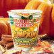 Product shot of Nissin Cup Noodles Pumpkin Spice flavor against autumnal pumpkin backdrop